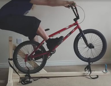 Photo of someone using a bmx to practice manuals on a wooden frame for support